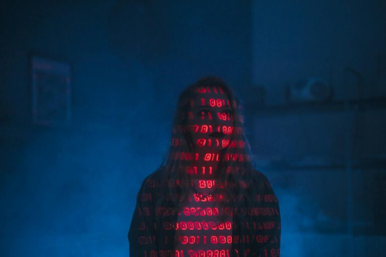 Best AI Security Tools for IT Professionals A mysterious silhouette with red binary code projected over the face, set against a dark, moody background.
