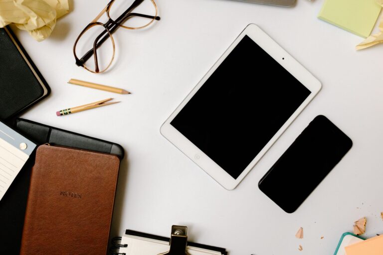 How to Implement MFA Across Your Organization Top view of a desk with gadgets, glasses, and notebooks in an organized arrangement.