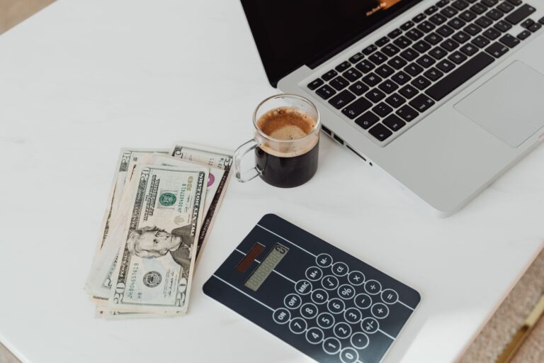 How to Set Up a Hybrid Cloud on a Budget A modern workspace featuring a calculator, cash, and laptop with coffee.