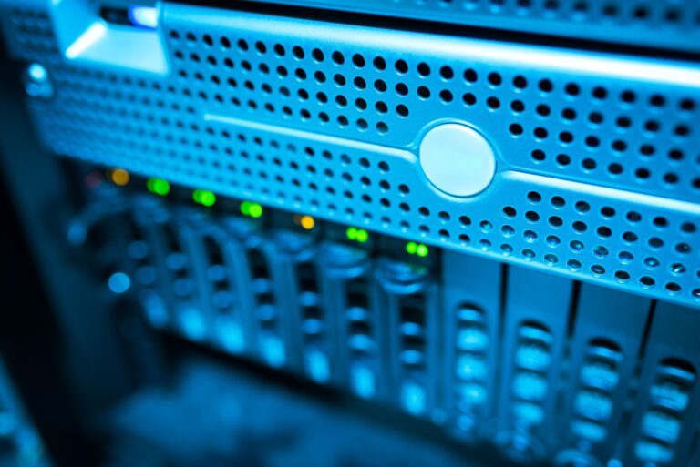 Best Monitoring Stacks for Self-Hosted Infrastructure Focused view of a modern data server rack with blinking lights in a blue-lit environment.